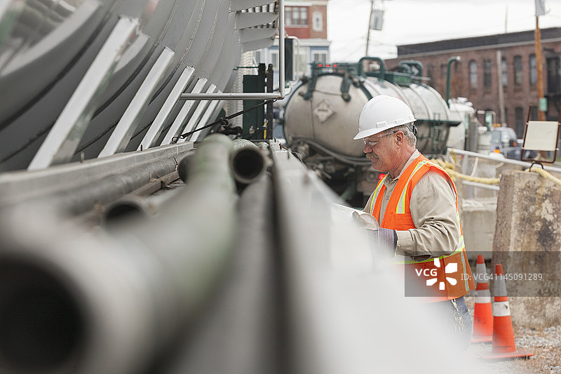 环保工程师在油罐车旁使用水桶图片素材