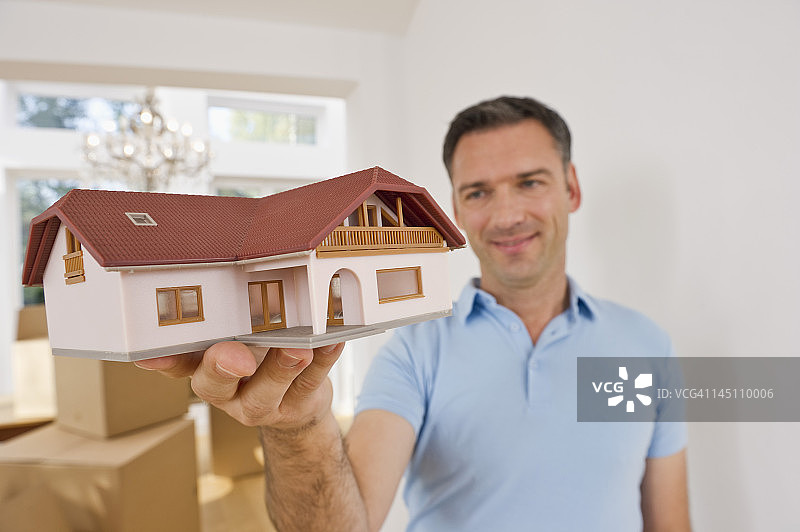 德国巴伐利亚格罗本策尔：拿着模型房的成熟男人在纸箱旁微笑图片素材