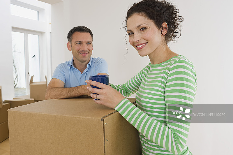 德国巴伐利亚格罗本策尔：情侣站在纸板箱旁，手拿咖啡杯微笑图片素材