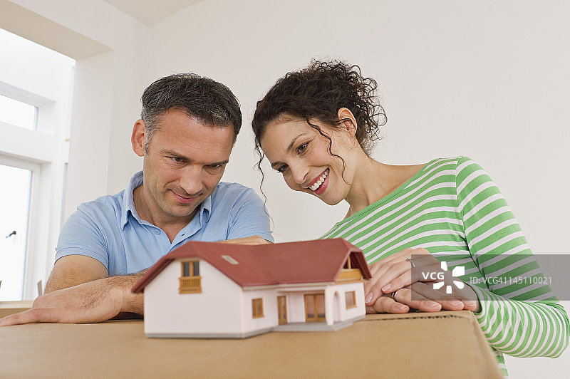 面带微笑的夫妇与纸箱模型房屋图片素材
