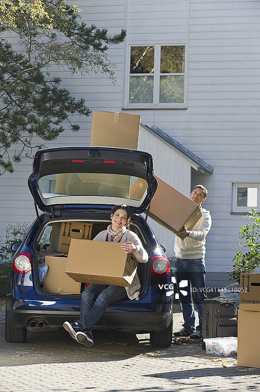 德国巴伐利亚Grobenzell，情侣搬运箱子到车上，微笑图片素材