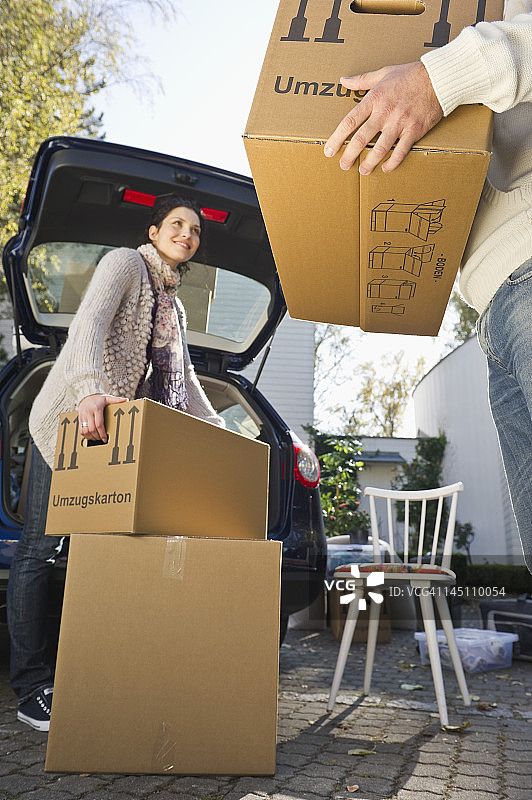 德国巴伐利亚Grobenzell，情侣搬运箱子到车上，微笑图片素材