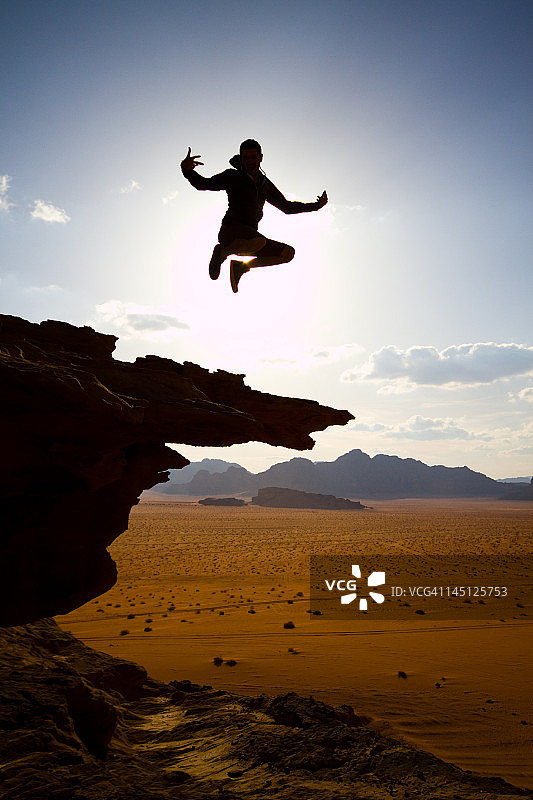 沙漠悬崖上的跳跃剪影图片素材