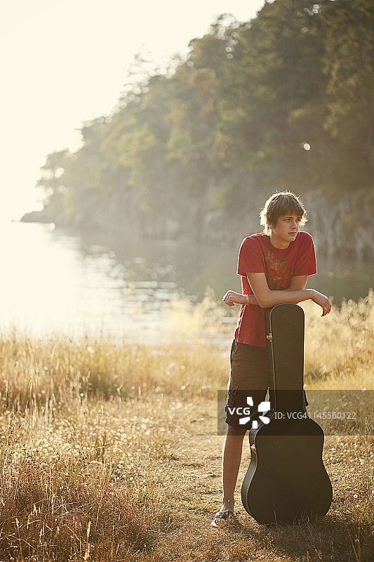 男孩倚靠在吉他盒上图片素材