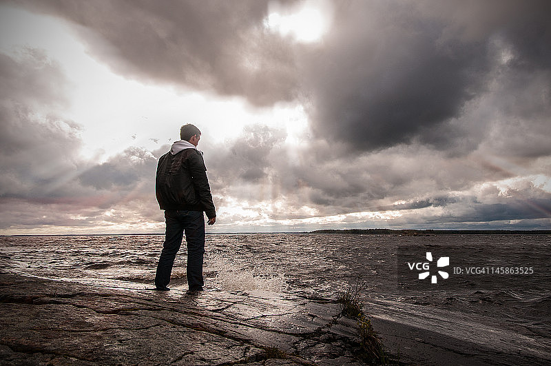 男子站在岩石海滩上图片素材