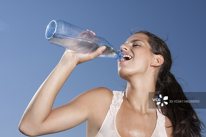 年轻女人在户外喝瓶装水图片素材