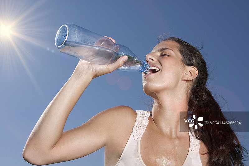 年轻女人在户外喝瓶装水图片素材