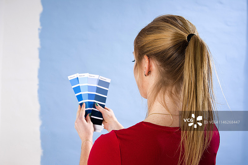 年轻女人在墙边展示色卡图片素材