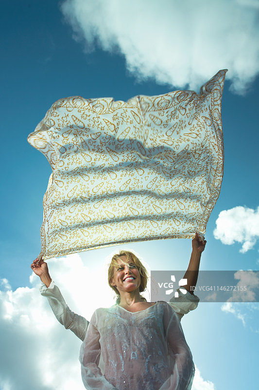 在微风中手持纱笼遮住女人头的人图片素材