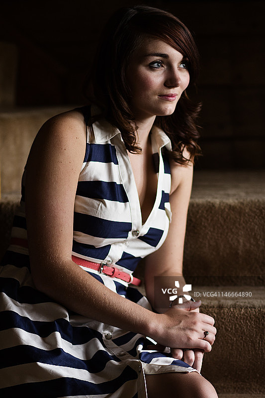 年轻女子穿着条纹连衣裙在楼梯上图片素材