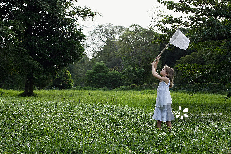 年轻女孩用网追逐蝴蝶图片素材