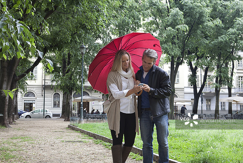 情侣在公园散步时查看短信图片素材