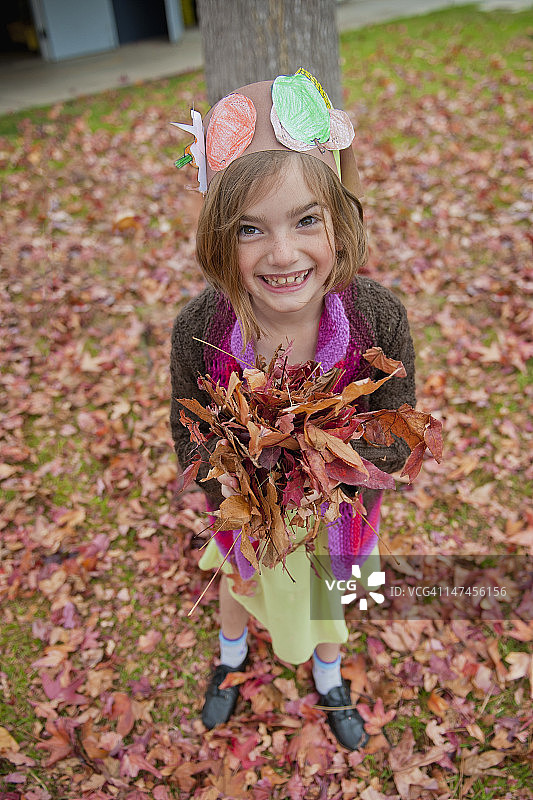 淘气女孩双手捧满秋叶图片素材