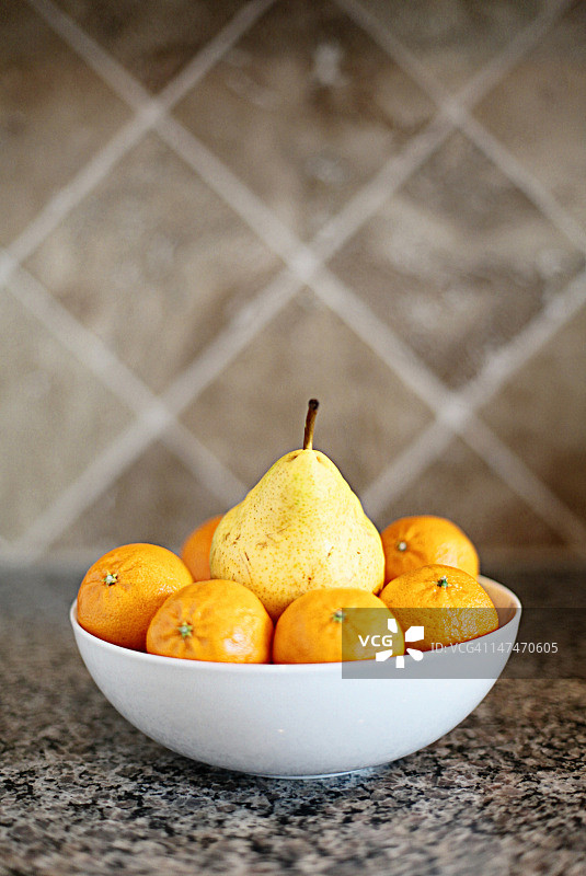 白色碗中被橙子包围的梨图片素材