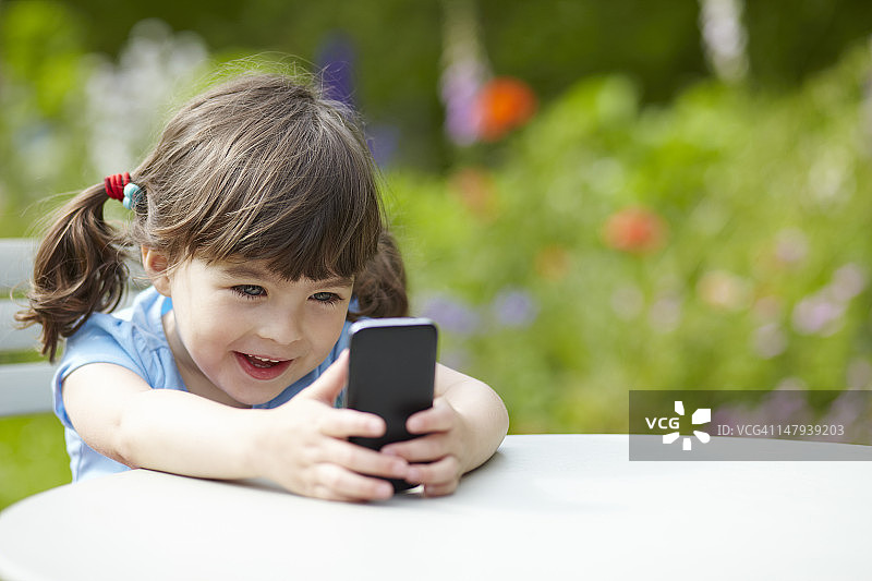 在花园里用手机的少女图片素材