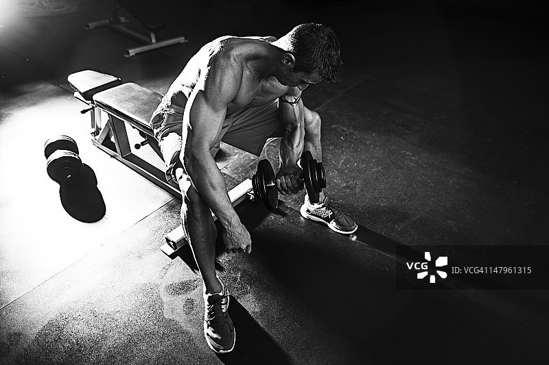 男人坐在长椅上举重图片素材