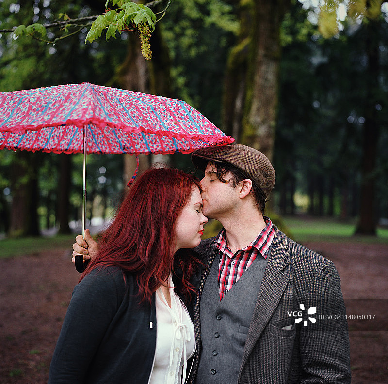 在公园里打伞亲吻的情侣图片素材