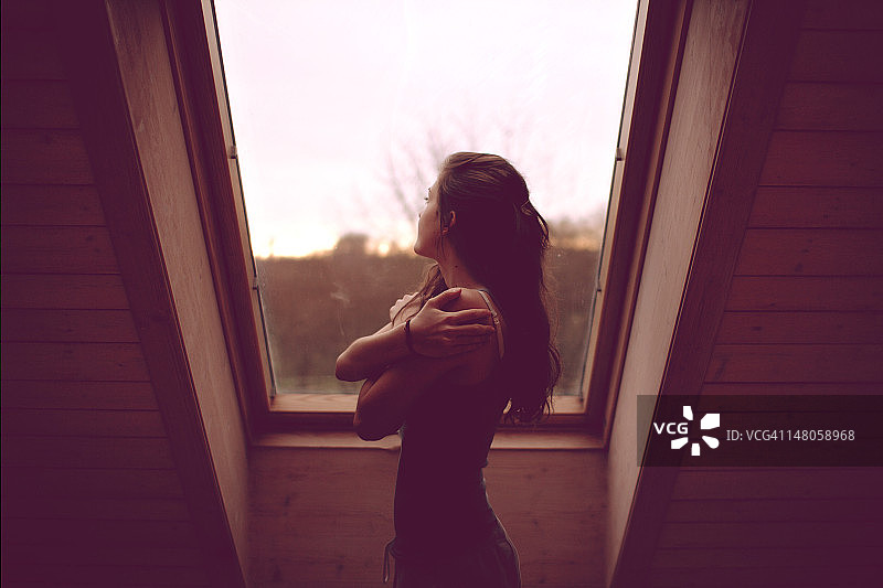 透过窗户看东西的年轻女人图片素材