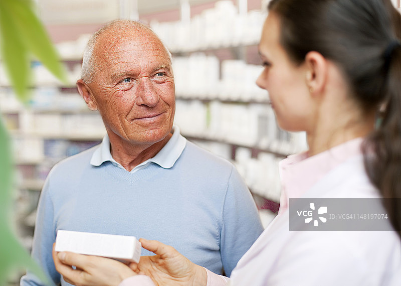 药剂师在药店与患者交谈。图片素材