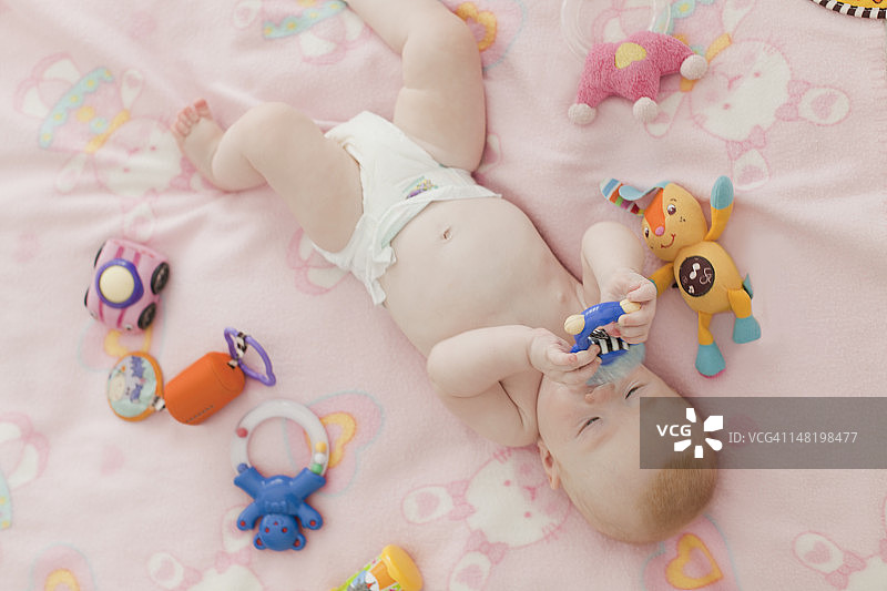 宝宝在毯子上啃咬摇铃图片素材
