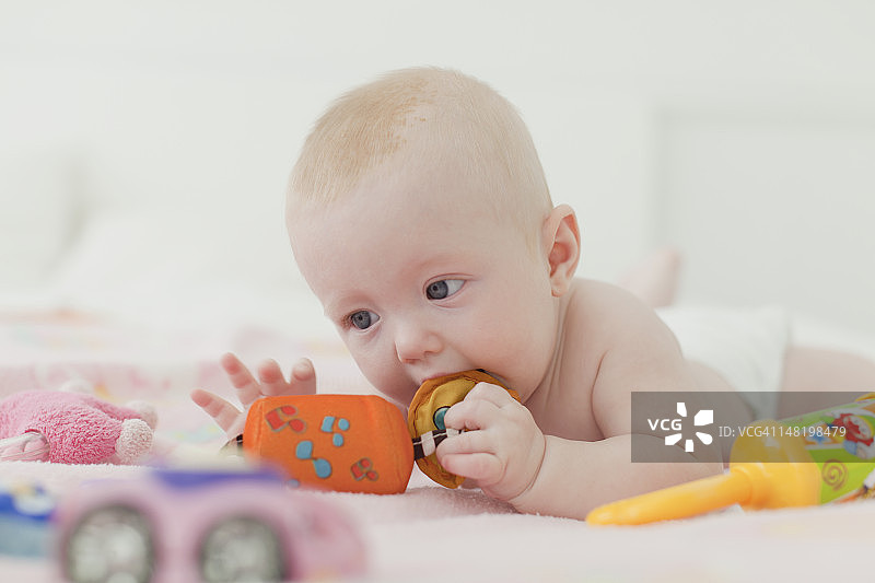 宝宝在毯子上啃咬摇铃图片素材