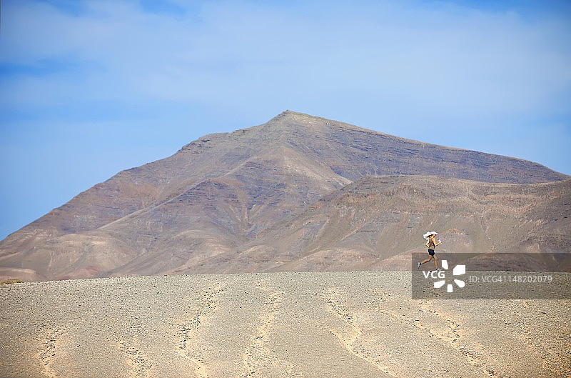 赛跑者在沙漠中慢跑，手拿饮料瓶图片素材