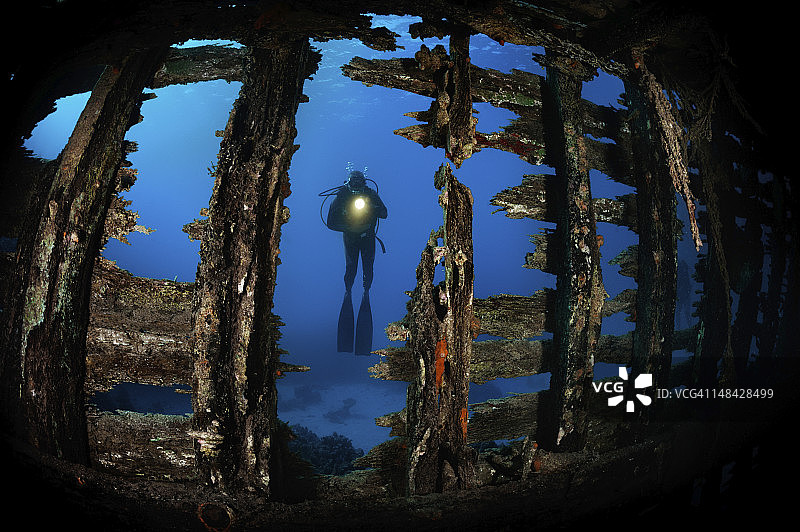 沉船残骸后面的水肺潜水员图片素材