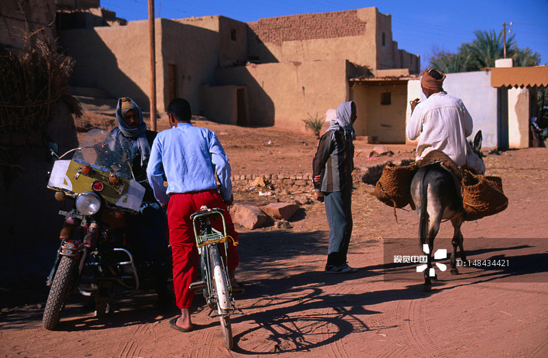 男人在村里的街道上使用三种不同的交通工具图片素材