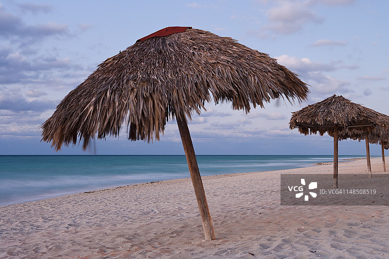 黄昏时分带茅草遮阳伞的海滩图片素材