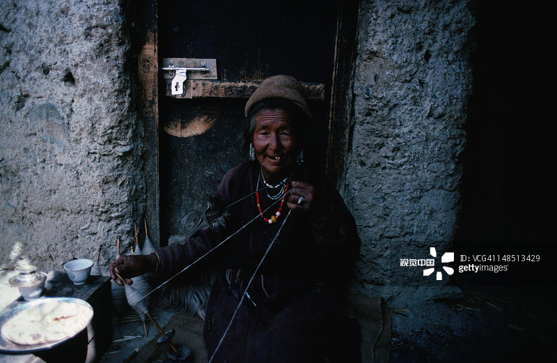 在拉马约鲁村，一位老妇人在自家门前编织图片素材