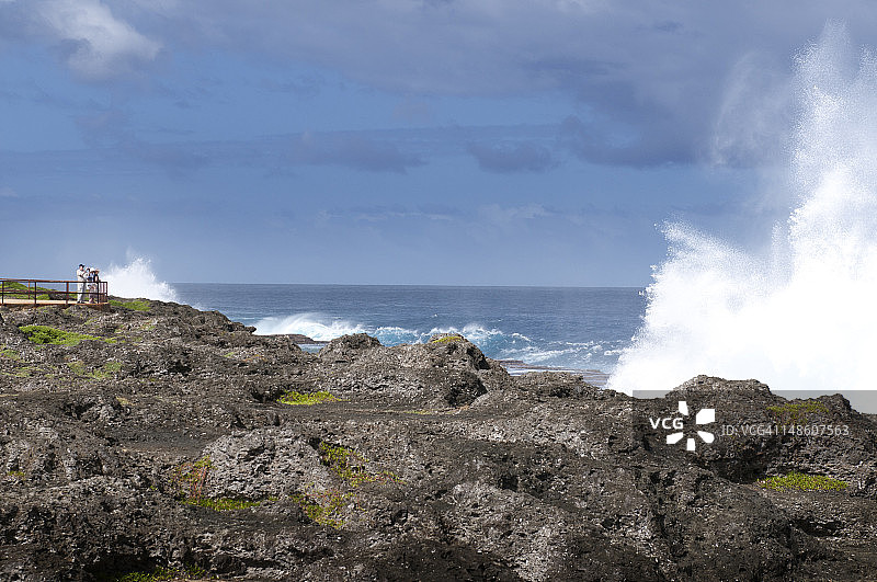 游客观赏岩石阶梯海岸线上的喷水孔图片素材