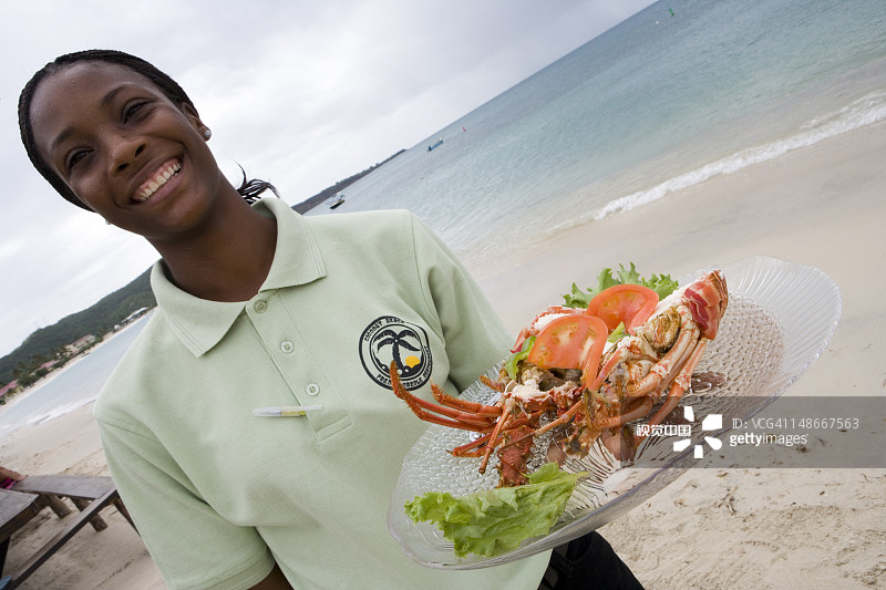 女服务员端着龙虾午餐，椰子海滩法式克里奥尔餐厅，格兰德安斯海滩图片素材