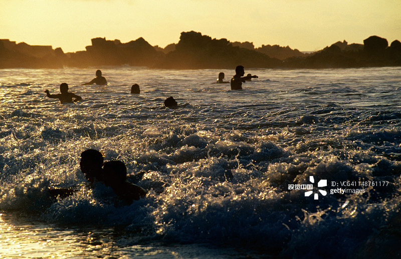日落时分的游泳运动员和趴板冲浪者图片素材
