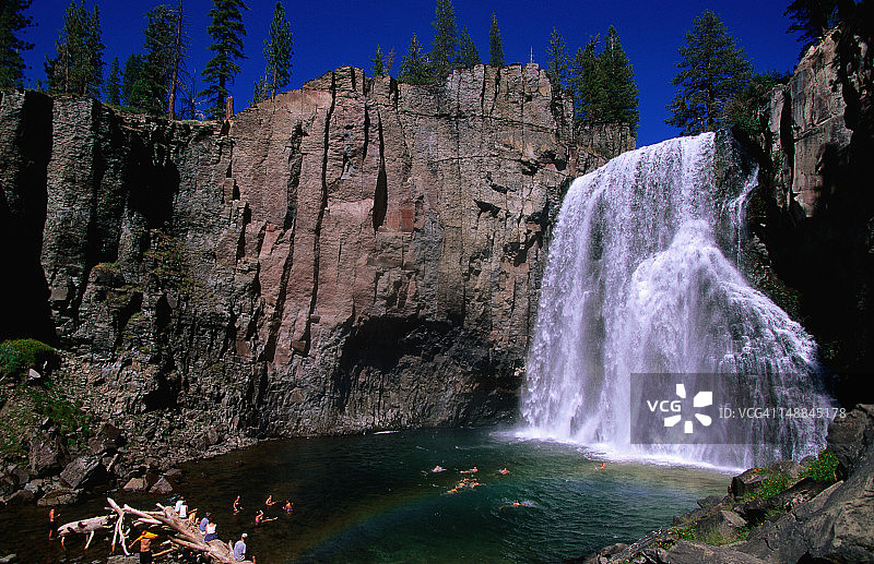 彩虹瀑布与在底部水池游泳的游客图片素材
