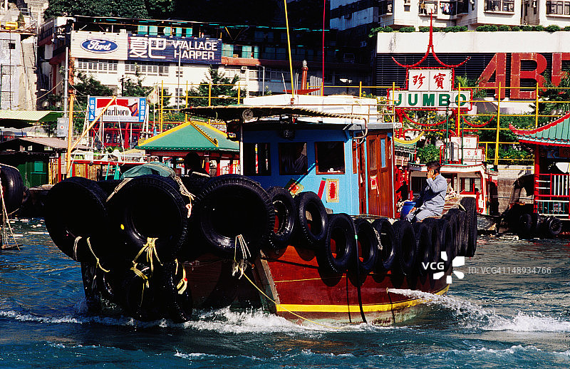 男人坐在香港仔港口拖船的船尾打电话图片素材