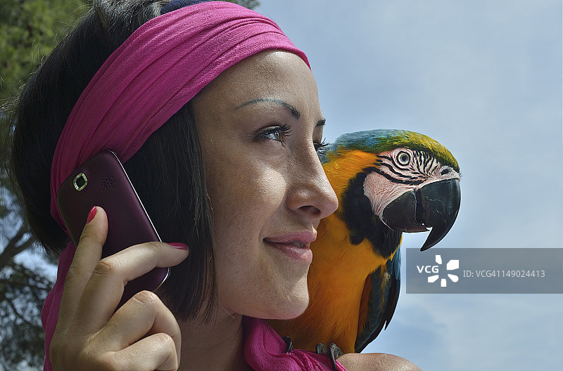 肩膀上站着鹦鹉的打电话的女人图片素材