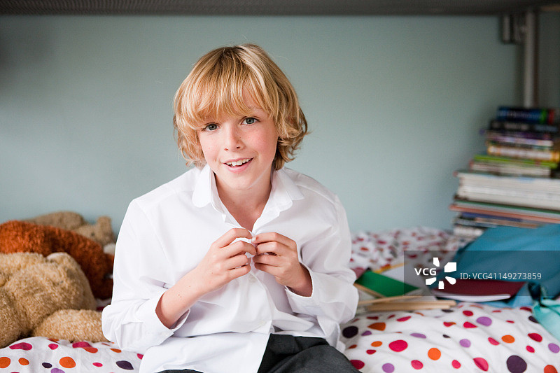 在卧室里系校服纽扣的男孩图片素材