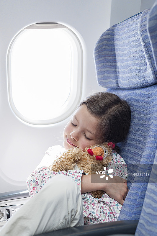 女孩在飞机上拥抱毛绒玩具图片素材