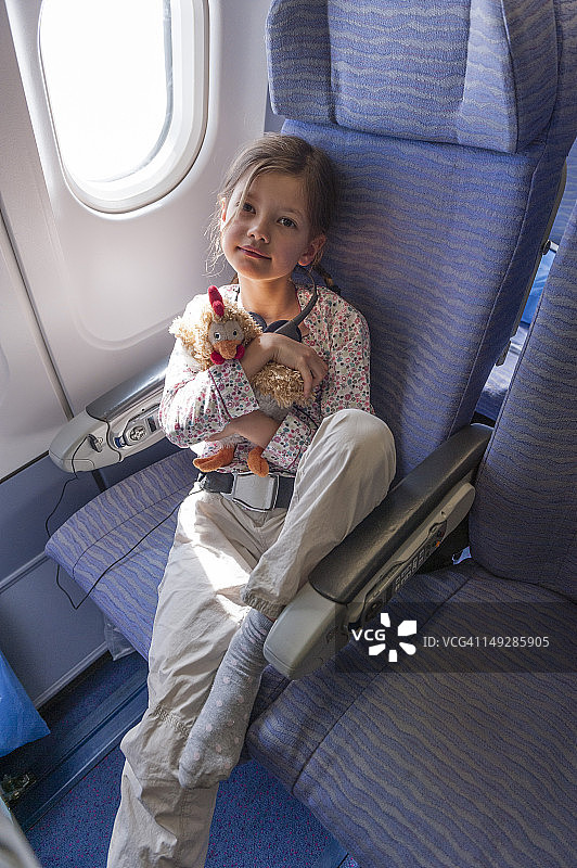 女孩在飞机上抱着毛绒玩具，肖像图片素材