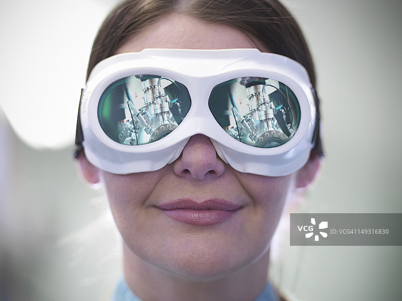 佩戴激光护目镜的女科学家肖像，材料科学实验舱在护目镜中反射图片素材