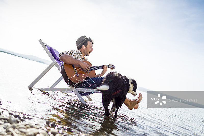 男子与狗在小溪边的草坪椅上图片素材