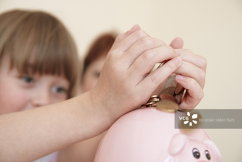 女孩往小猪存钱罐里放钱图片素材