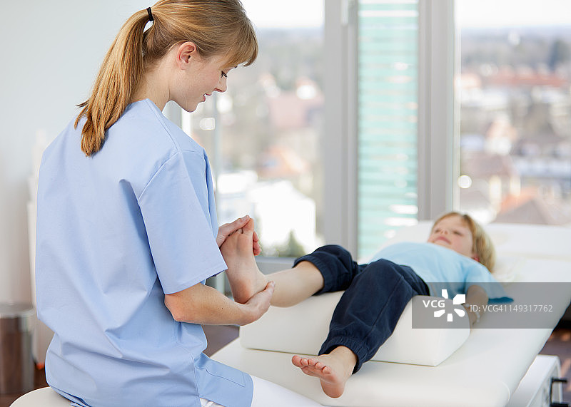 医生在诊室检查男孩的脚图片素材