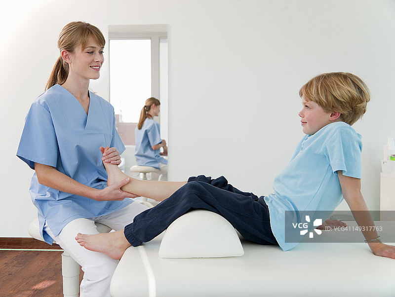 医生在诊室检查男孩的脚图片素材
