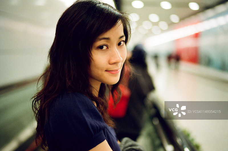 年轻女人站在自动扶梯上微笑图片素材