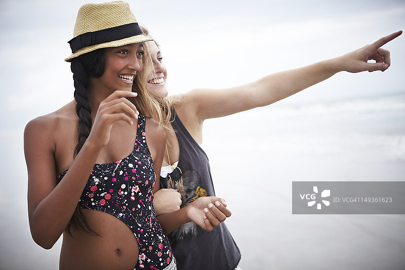 两名年轻女子在海滩上面向大海欢笑图片素材