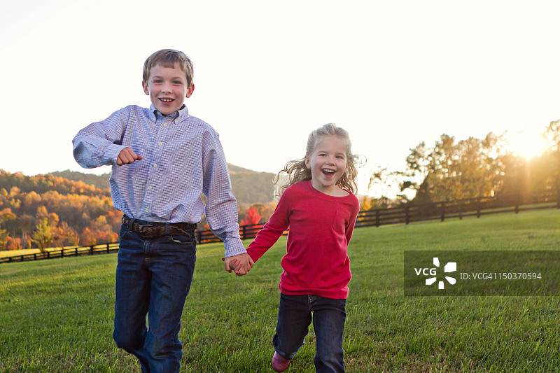 兄弟姐妹手牵手在田野里奔跑图片素材