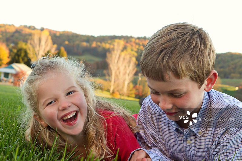 兄弟姐妹躺在草地上欢笑图片素材