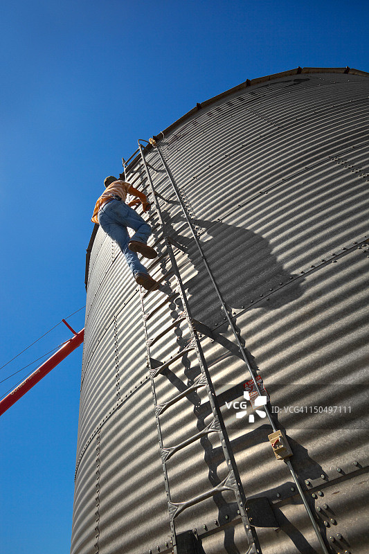 农场工人在粮仓上爬梯子图片素材