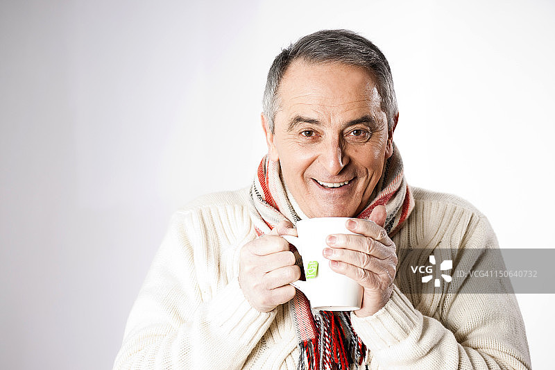 穿着冬装喝茶的快乐老年男人图片素材